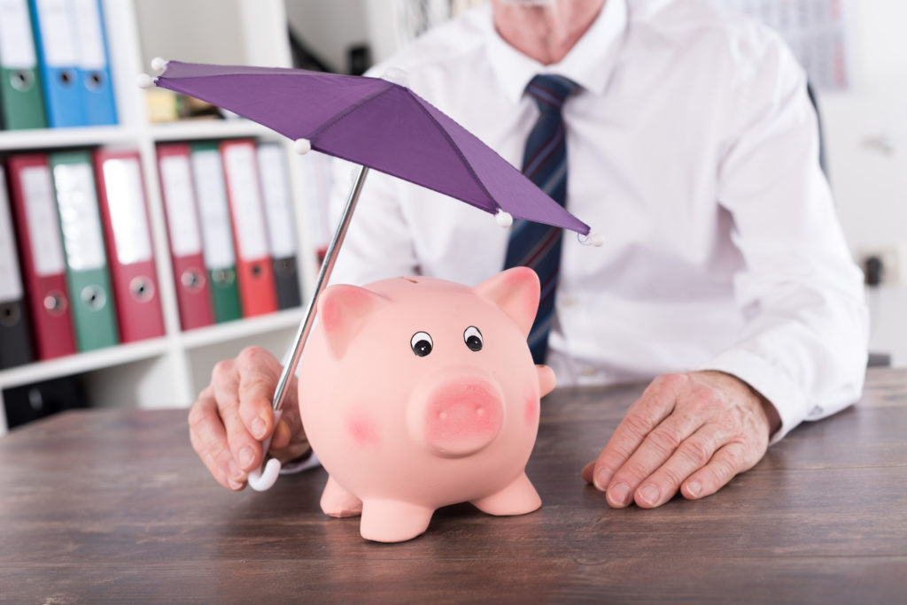 a man holding an umbrella over a piggy bank representing money protection