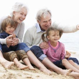 grandparents sitting on the beach with their grandchildren