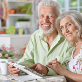 elderly couple smiling while using a tablet