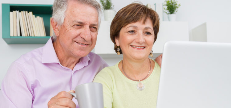 elder couple happily looking at a computer together