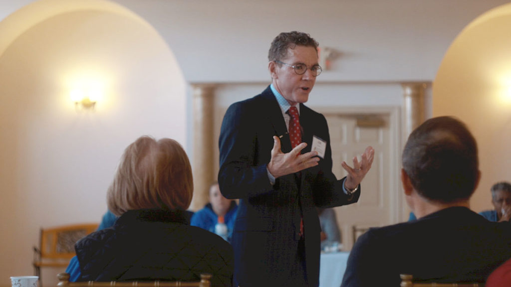 Joseph Cordell standing in the middle of a room giving a speech